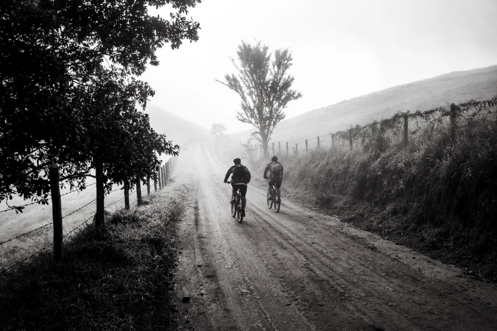 two people riding bikes in the foggy countryside